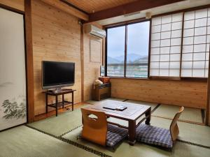 sala de estar con TV, mesa y sillas en 大和屋ホテルいろは, en Nikko