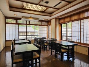 un comedor con mesas, sillas y ventanas en 大和屋ホテルいろは, en Nikko