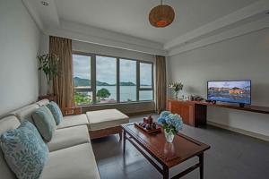 a living room with a couch and a tv at Sheraton Huizhou Beach Resort in Huidong