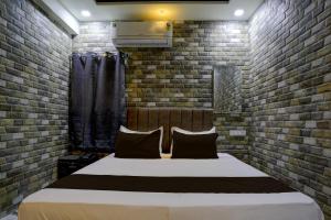 1 dormitorio con 1 cama en una pared de ladrillo en Collection O Hotel Leo Inn, en Rajkot