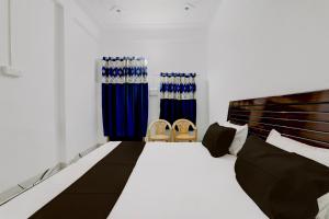 1 dormitorio con 1 cama con cortinas azules y 2 sillas en OYO RD PALACE, en Auraiya