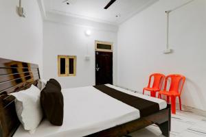1 dormitorio con 1 cama y 2 sillas de color naranja en OYO RD PALACE, en Auraiya