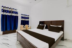 1 dormitorio con 1 cama grande y cortinas azules en OYO RD PALACE, en Auraiya