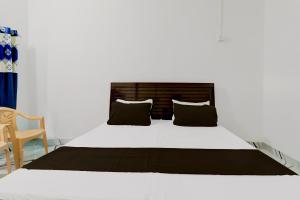 Una cama blanca con almohadas negras en un dormitorio en OYO RD PALACE, en Auraiya
