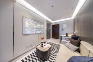 a living room with a couch and a tv on a wall at Bailai Qingju - Shenzhen Convention and Exhibition Center in Shenzhen