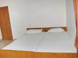 - un lit blanc avec deux oreillers dans l'établissement Hotel Teerth Guest House Inn Varanasi, à Varanasi