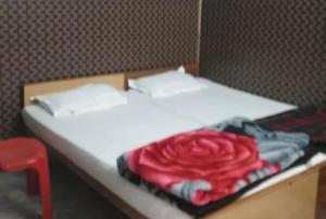 uma cama branca com um cobertor rosa vermelho em Hotel Teerth Guest House Inn Varanasi em Varanasi