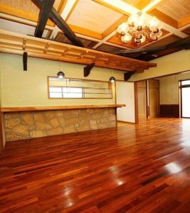 a large room with a wooden floor and a stone wall at ゆーみー. in Meinohama