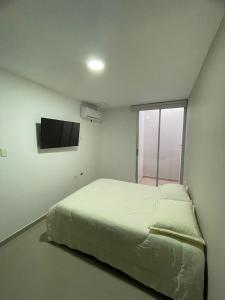 um quarto com uma cama e uma televisão na parede em HERMOSO APARTAMENTO EN VALLEDUPAR em Valledupar
