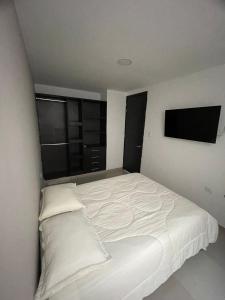 uma cama branca num quarto com uma televisão de ecrã plano em HERMOSO APARTAMENTO EN VALLEDUPAR em Valledupar
