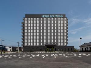 a hotel building with a parking lot in front of it at Hotel Route Inn Tokushima Airport -Matsushige Smartinter- in Matsushige