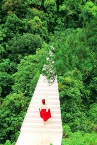 Uma mulher num vestido vermelho a caminhar por um caminho branco. em Thung Lũng Tình Yêu Homestay Tam Đảo em Vĩnh Phúc