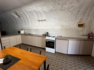 a kitchen with white cabinets and a table and a stove at Desert View Apartments in Coober Pedy