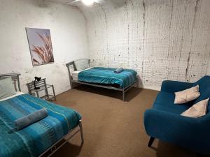 Cette chambre comprend un lit, un canapé et une chaise. dans l'établissement Desert View Apartments, à Coober Pedy