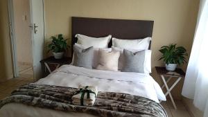 a bedroom with a large bed with white pillows at Olivia Pines Guesthouse in Krugersdorp