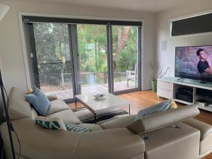 sala de estar con sofá y TV en Tranquil Getaway Wifi Netflix Pet friendly en Venus Bay