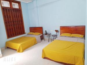1 Schlafzimmer mit 2 Betten mit gelber Bettwäsche und einem Tisch in der Unterkunft Nguyên căn Homestay 4 phòng ngủ sát biển in Sầm Sơn