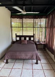 a bedroom with a bed in a room with windows at Casa la Picola in Sierpe