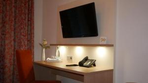een hotelkamer met een bureau, een telefoon en een televisie bij Hotel Garni Alte Post in Schallbach