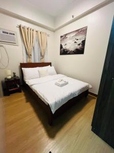 Amiela’s Place في Trece Martires: غرفة نوم بسرير كبير مع شراشف بيضاء