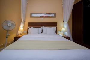 a bedroom with a white bed with two lamps and a fan at Capital Heights Hotel in Nairobi