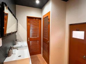 a bathroom with a sink and a wooden door at ゲストハウス JOOOY Hotel 奄美 in Amami