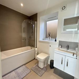 a bathroom with a toilet and a tub and a sink at Southborough Suite in Kent