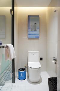 a bathroom with a toilet and a picture on the wall at Tianjin Polar Ocean Hotel in Binhai