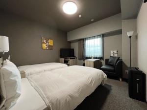 ein Hotelzimmer mit 2 Betten und einem Stuhl in der Unterkunft Hotel Route Inn Tokushima Airport -Matsushige Smartinter- in Matsushige
