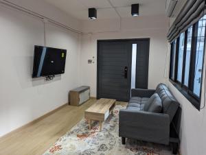 a living room with a couch and a tv at Cloud9 Hometel - Entire House 3BR 170m to BTS Private Quiet & Comfy in Bangkok