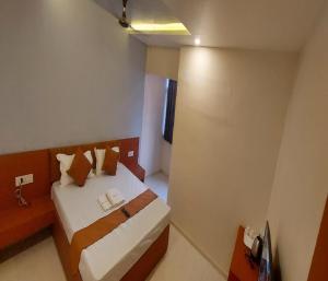 een kleine slaapkamer met een bed met witte lakens en kussens bij Hotel Kapish International Solapur 400 mts from Bus Stand and 500 mtr from railway station in Solapur