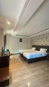 a bedroom with two beds and a television in it at NURIS HOTEL in Lampung