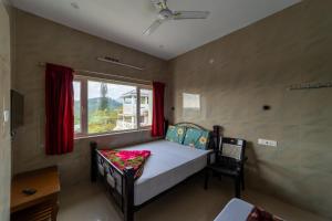 um pequeno quarto com uma cama e uma janela em Sri Nandha Luxury Comforts em Valparai