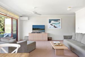 a living room with a couch and a tv at Fathoms 8 in Mollymook