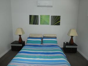 a bedroom with a bed with two lamps on both sides at Tranquil Getaway Wifi Netflix Pet friendly in Venus Bay