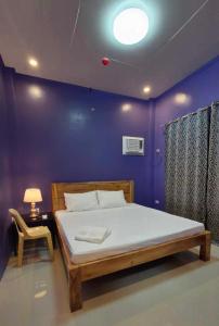 una camera con un letto con una parete viola di Drossgold Pension House a Tubigon