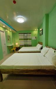 two beds in a room with green walls at Drossgold Pension House in Tubigon