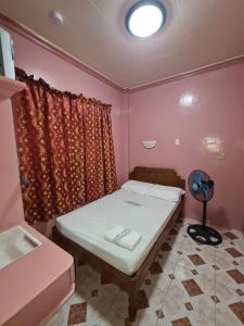a small bedroom with a bed and a window at Drossgold Pension House in Tubigon