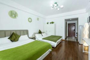 a hotel room with two beds with green sheets at Dalian Hong Xi Yuan Apartment Wanda Plaza in Dalian