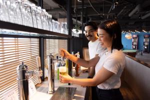 a man and a woman standing at a bar preparing drinks at TWIN LINE HOTEL YANBARU OKINAWA JAPAN Formerly Okinawa Suncoast Hotel in Nago