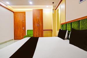 a bedroom with a large bed with a green headboard at OYO Hotel Shree in Dewās