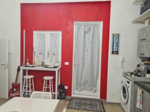 une cuisine avec un mur rouge et un comptoir avec des tabourets dans l'établissement Monolocale piano terra 35mq, à Francavilla al Mare