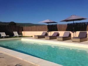 uma piscina com espreguiçadeiras e guarda-sóis em Villa de 6 chambres avec piscine privee jardin clos et wifi a Saint Saturnin les Apt em Saint-Saturnin-dʼApt