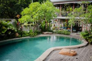 a swimming pool in front of a building with trees at Ecozy Dijiwa Canggu in Canggu