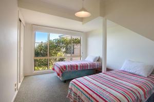 two beds in a room with a window at Spectacular Views in Mollymook