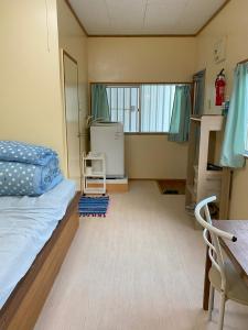 1 dormitorio con cama, escritorio y ventana en 海の丘 ステイ umioka stay, en Nakijin