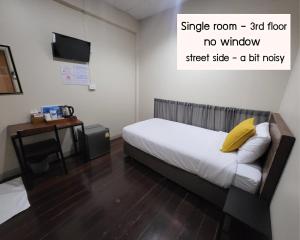 曼谷的住宿－Achcha hotel - itsaraphap MRT station - Wat Arun，一间卧室配有一张带黄色枕头的床和一张书桌