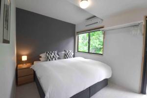 ein Schlafzimmer mit einem großen weißen Bett und einem Fenster in der Unterkunft Hakuba Cottage Karamatsu in Hakuba