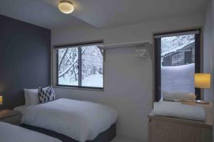 a bedroom with a bed and a window with snow at Hakuba Cottage Karamatsu in Hakuba