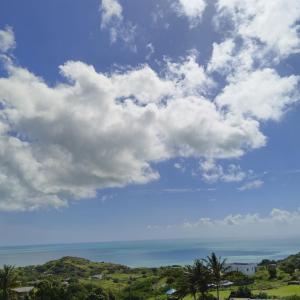 a blue sky with white clouds and the ocean at Residence de la Montagne in Quatre Vents